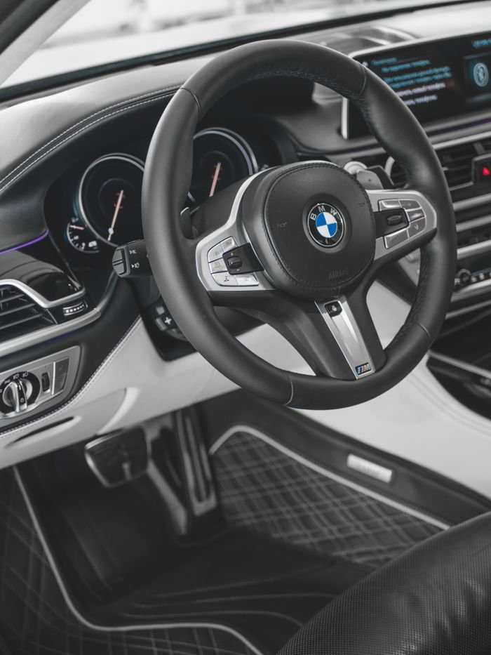 Close-up of a BMW car steering wheel showcasing luxury leather interior details.